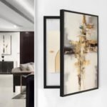 لوحة كانفس بألوان دافئة وتصميم تجريدي، بإطار أسود أنيق لتغطية طبلون الكهرباء.