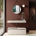 مرآة جدارية دائرية بلون ذهبي مع إطار جلدي، تضفي لمسة عصرية على تصميم الحمام.