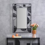 مرآة جدارية بتصميم هندسي عصري وإطار معدني أسود، تضيف لمسة أنيقة لأي مساحة.