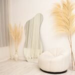 مرآة جدارية بتصميم عصري، شكل غير منتظم، مع إطار معدني، تعكس الضوء وتضفي لمسة أنيقة على المكان.