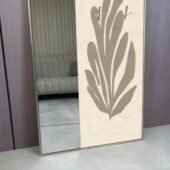 لوحة فنية تجمع بين مرآة وإكسسوارات علاقات بتصميم نباتي بلون بيج، تضيف لمسة عصرية للمساحات الداخلية.