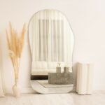 مرآة جدارية بتصميم منحني، لون فضي، تعكس الأضواء وتضفي لمسة عصرية على الديكور.
