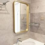 مرآة جدارية بإطار ذهبي، تصميم عصري، مثالية لتزيين الحمام وإضفاء لمسة أنيقة.