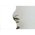 مرآة جدارية بتصميم منحني، إطار أبيض، تضفي لمسة عصرية على الديكور الداخلي.