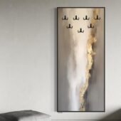 لوحة فنية جدارية بتصميم عصري، بألوان رمادية وذهبية، مع شماعات أنيقة لتعليق العبايات.