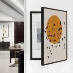 لوحة كانفس بتصميم دائري باللون البرتقالي مع طيور سوداء، إطار أسود، تناسب تغطية طبلون الكهرباء.