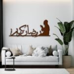 لوحة خشبية مودرن بلون بني تحتوي على نقش "رمضان كريم" مع شكل مصلي، تضيف لمسة دافئة للمساحات.