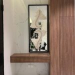 مرآة كلاسيكية بتصميم جبسي مبتكر، إطار أسود وزخارف بيضاء تعكس الأناقة والحداثة.