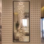 مرآة كلاسيكية بإطار أسود وتصميم جبسيات مبتكر بأشكال نباتية، تضيف لمسة فنية للديكور.
