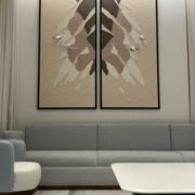 لوحة جبسية ثنائية الأجزاء بألوان دافئة وتصميم منسوجات فنية، إطار أسود، تعزز جمالية المكان.