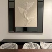 مرآة سوداء بإطار أنيق تحتوي على لوحة فنية بيضاء بتصميم ثلاثي الأبعاد.