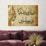 لوحة قماشية بتصميم إسلامي بألوان دافئة مع برواز مجوف، تحتوي على نص مكتوب بخط عربي جميل.