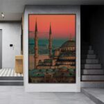 لوحة قماشية بتصميم مودرن تظهر معالم معمارية إسلامية بألوان دافئة في إطار مجوف أنيق.
