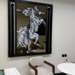 لوحة فنية مرسومة على مراية، تظهر خيلًا بتصميم أنيق باللونين الأبيض والأسود، بإطار أسود عصري.